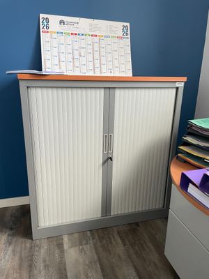 une armoire sur laquelle est posé un calendrier, dans un coin de la pièce