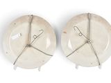 pair of white ceramic plates with wire handles on white background