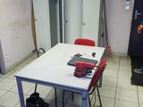 a white table with red chairs in a room with lockers