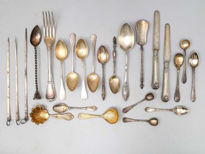 de nombreuses cuillères en argent et des cuillères ordinaires disposées sur une table