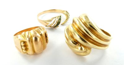 deux bagues en or et une bague posée sur une surface blanche