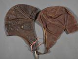 pair of brown leather aviator ' s hats on a gray surface