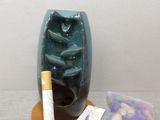 a small blue vase with a cigarette and a bag of cigarettes