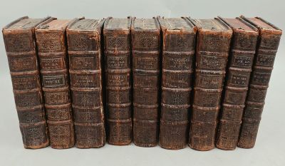 six vieux livres empilés sur une surface blanche