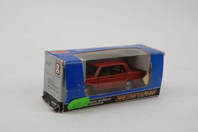 a red toy car in a blue box on a white surface