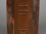 an old book with a brown cover sitting on top of a table