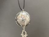 a close up of a necklace with a silver ball on a string