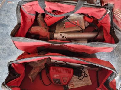 deux sacs rouges contenant des outils, posés par terre