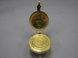 une image représentant une montre de poche en or sur laquelle figure une boussole