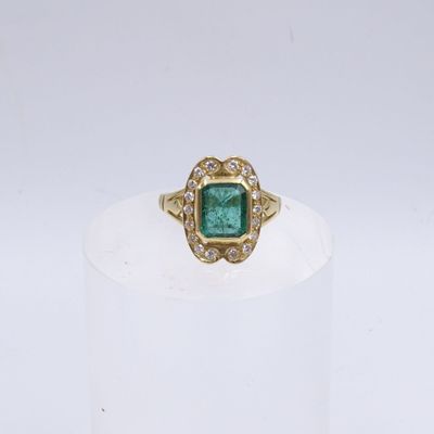 un gros plan d'une bague en or sertie d'une émeraude entourée de diamants