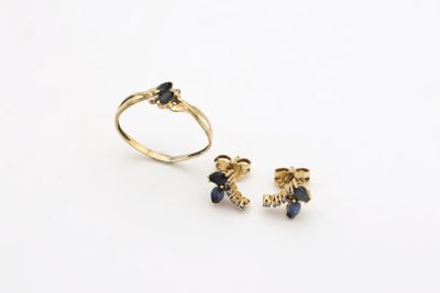 a close up of a gold ring and a pair of earrings on a white surface