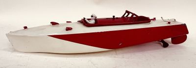 un petit bateau jouet rouge et blanc posé sur une surface blanche
