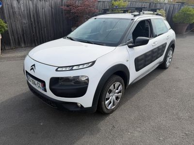 a white citrole parked in a parking lot next to a fence