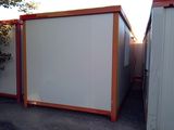 a picture of a white and red container house next to a building