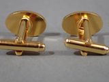 pair of gold tone cufflinks on a gray surface