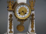 a white and gold clock with statues around it