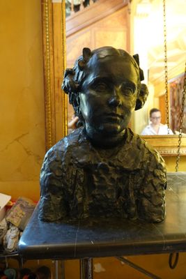 un buste en bronze représentant une femme assise, posé sur une table