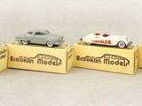 three small toy cars are sitting on top of boxes on a white surface