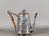 une théière en argent avec une anse en bambou posée sur une table