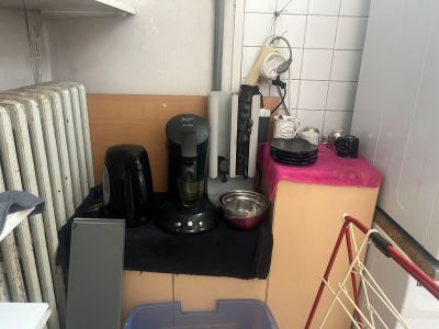 une petite cuisine équipée d'une cuisinière, d'un réfrigérateur, d'un micro-ondes et d'autres appareils électroménagers