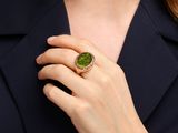 La femme porte une bague sertie d'une pierre verte.