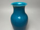 blue vase with a gold rim sitting on a white surface