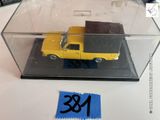 un petit camion jaune dans une boîte transparente posée sur une table