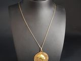 a gold necklace with a bird on it on a mannequin