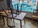several wooden chairs are sitting in front of a window with a painting on the wall