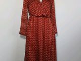 une robe rouge posée sur un mannequin, devant un mur blanc