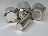 four silverplated salt and pepper shakers on a white surface