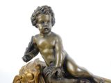 a bronze statue of a boy sitting on a rock
