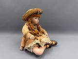 doll sitting on the floor wearing a straw hat and dress