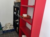 a red book shelf in the corner of a room