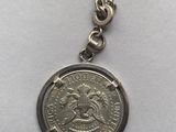 a close up of a coin on a chain on a white surface