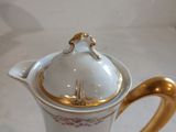 a white and gold coffee pot with a gold handle