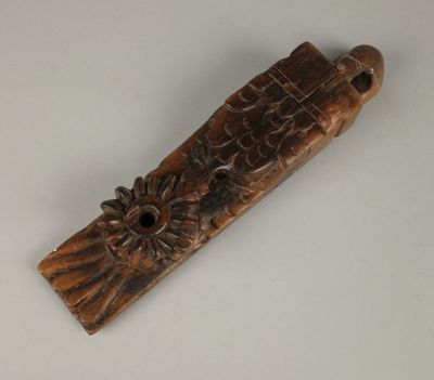 une vieille sculpture en bois représentant un oiseau sur lequel est posée une fleur