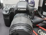 a canon camera sitting on a table next to a cell phone