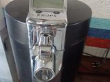 a coffee maker sitting on a table with a clock on it