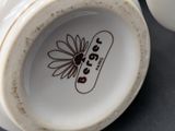 a close up of a white vase with a flower on it