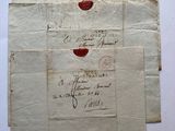 trois feuilles de papier sur lesquelles figurent des inscriptions à l'encre rouge, posées sur une table
