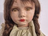 a close up of a doll with long brown hair
