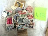 une pile de timbres posée sur une table à côté d'une boîte aux lettres jaune — c'est