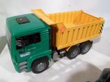 un camion-jouet vert avec un camion-benne jaune à l'arrière