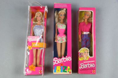 three barbie dolls are in a pink box on a table