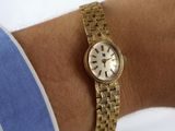 a woman wearing a gold watch on her wrist