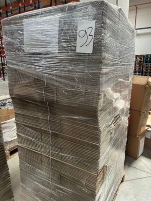 une grande pile de cartons dans un entrepôt, sur laquelle est apposée une étiquette de prix