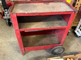 a red work cart with two shelves on it in a garage