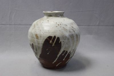 a white and brown vase with two hands painted on it
