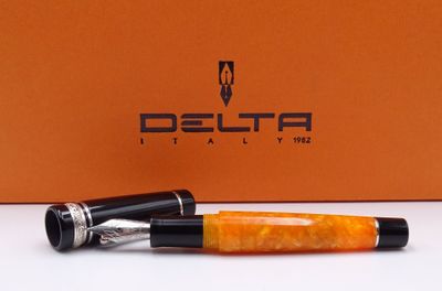 un stylo orange posé sur une table blanche, à côté d'une boîte orange